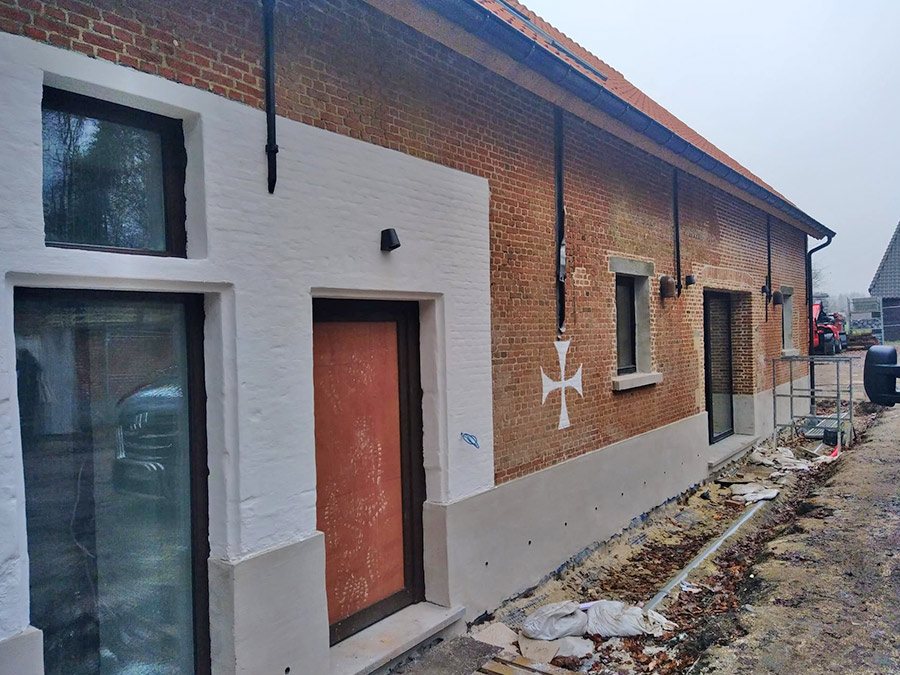 Hoeve met witte kalkpleister en bakstenen gevel